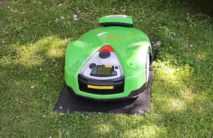 Ein Rasenmähroboter auf einer Ladestation.